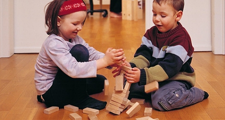 Kinder harmonisch spielend mit gesundem Spielzeug, Bauklötze stürzen um