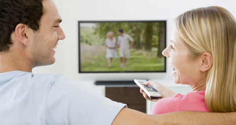 Paar sieht lachend fern, Wohnzimmer ist staubfrei durch Multimedia-Möbel