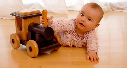 Spielendes Kleinkind mit Eisenbahn auf Vollholz-Parkett-Boden in Kinderzimmer